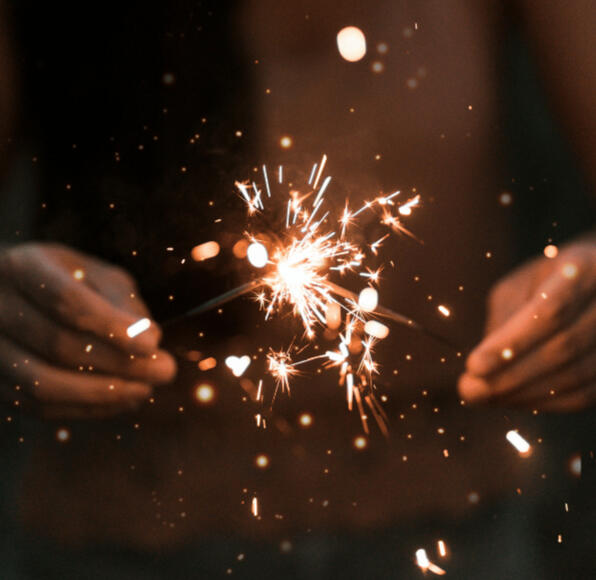 two hands come together to light a sparkler