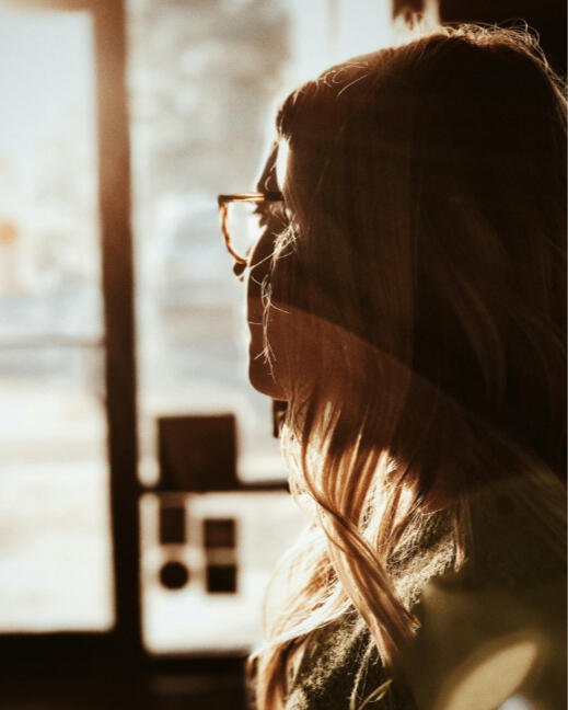 woman with glasses looking out a window